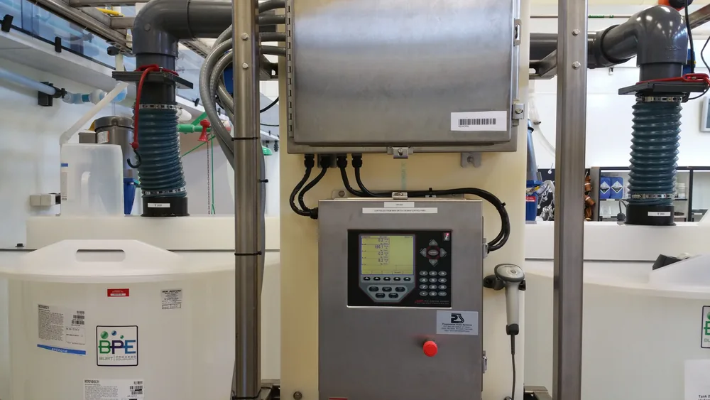 A filling and batching control panel with an indicator and emergency stop, plumbed to load-cell mounted supply tanks.